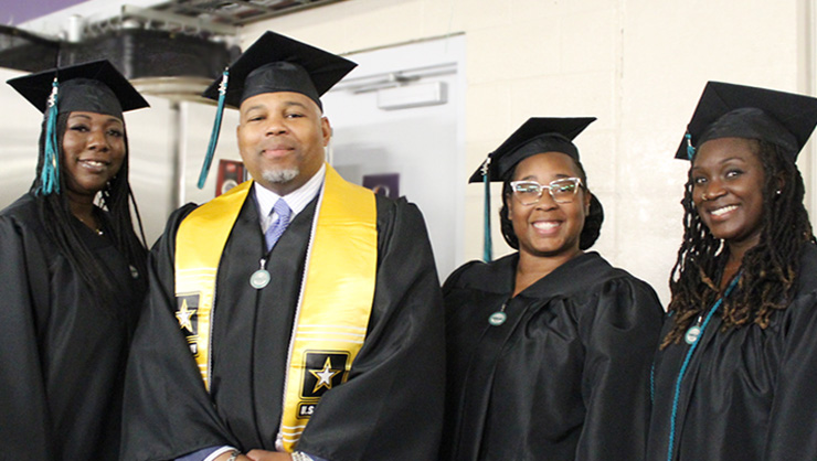 Three female and one male student at Commencement