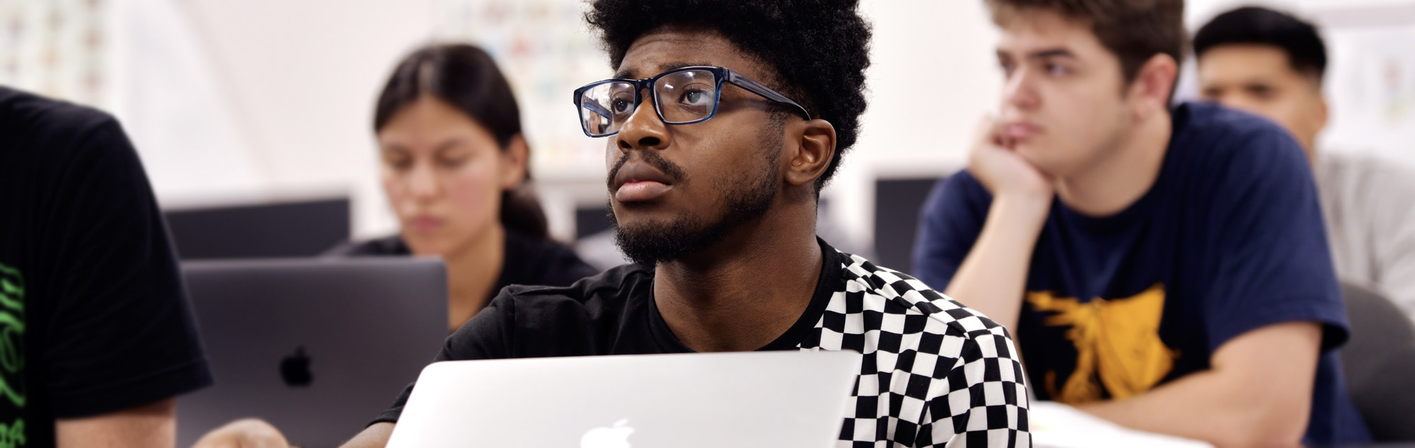 Student works on computer while listening to class lecture.