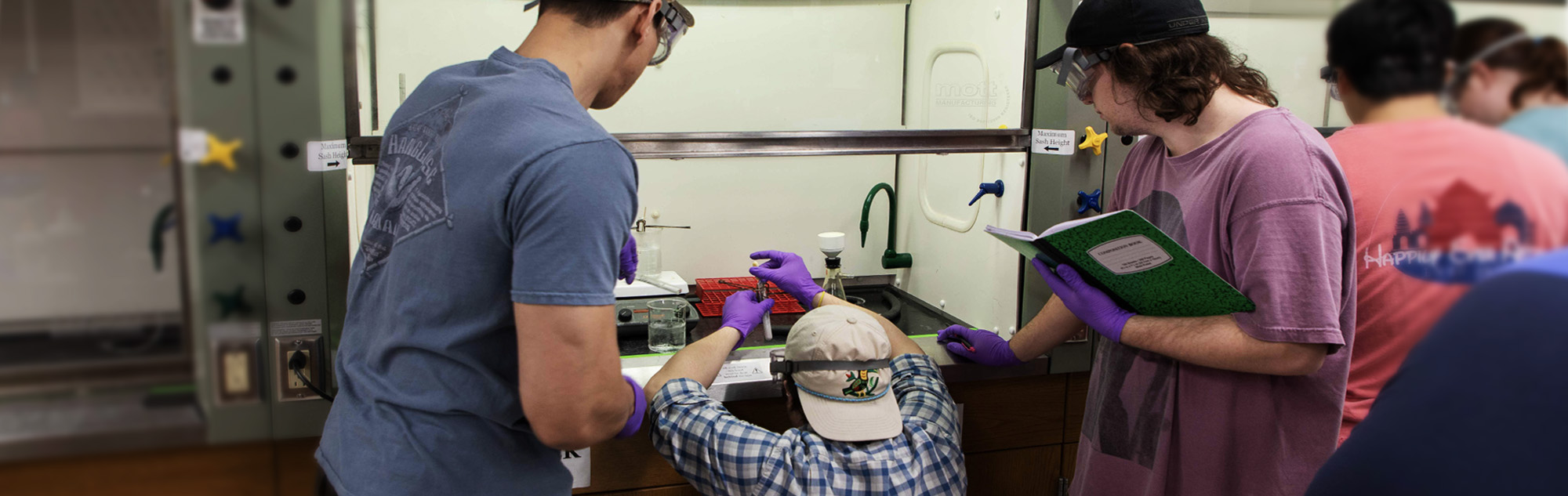 Three students conduct organic chemistry experiment.