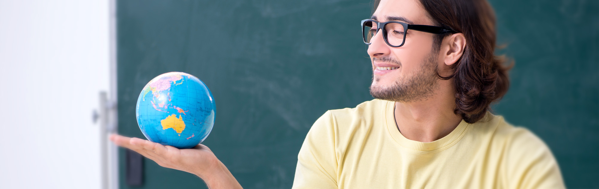 Male student looks at world globe.