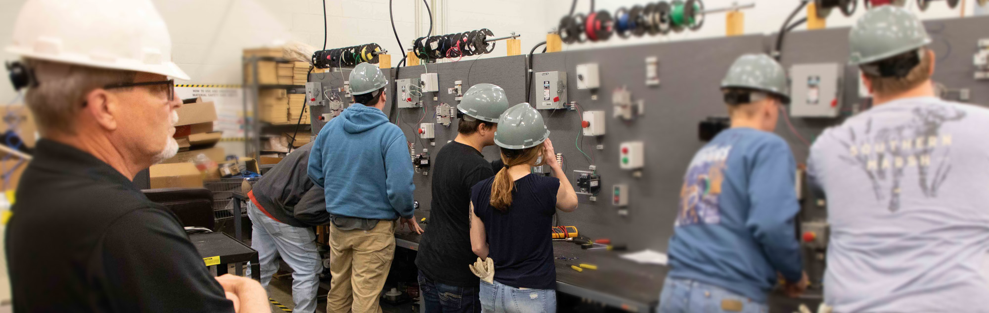 Students work on electrical boxes.