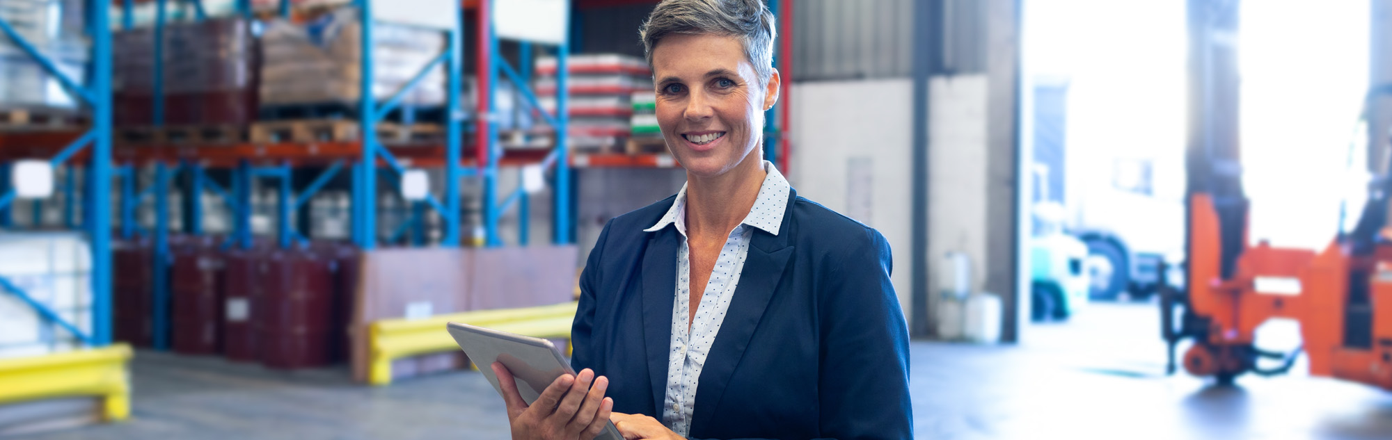 Student stands in warehouse with clip board.