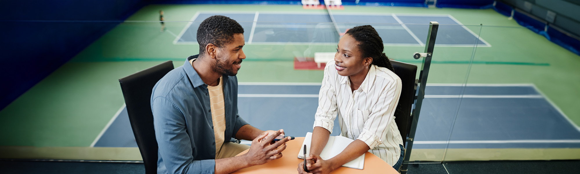 Man and woman attending business meeting at a sports facility.